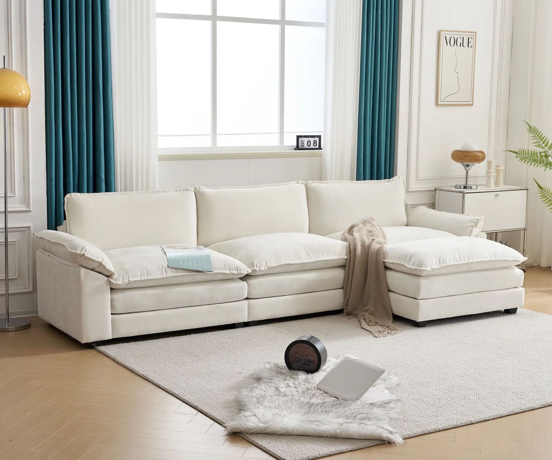 neutral living room with a large cushion style sleeper sofa L shaped section on a neutral rug with teal curtains behind