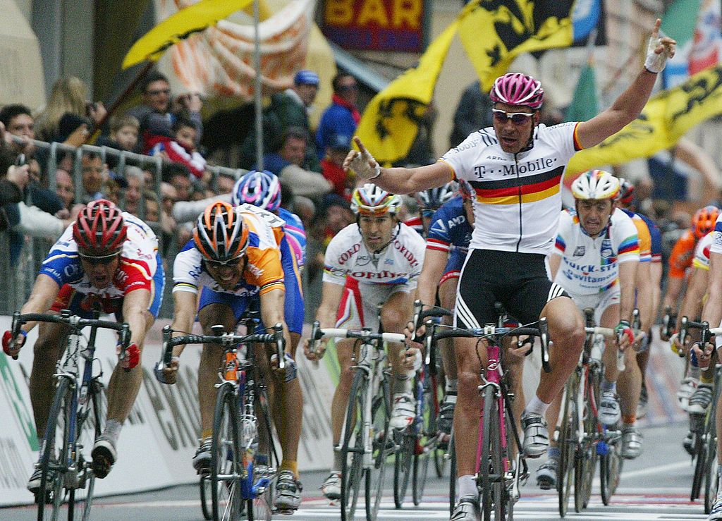 SAN REMO ITALY Spains Oscar Gomez Freire 2nd L crosses the finish line and wins the 95th edition of MilanSan Remo cycling race as Germanys Erik Zabel R raises his arms in San Remo 20 March 2004 Zabel finished second while Australian Stuart OGrady L finished third AFP PHOTO PAOLO COCCO Photo credit should read PAOLO COCCOAFP via Getty Images