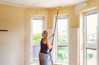 Woman painting a ceiling with a roller