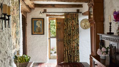 entrance hall with door open and grandfather clock with beams flagstone floor and white limewashed walls