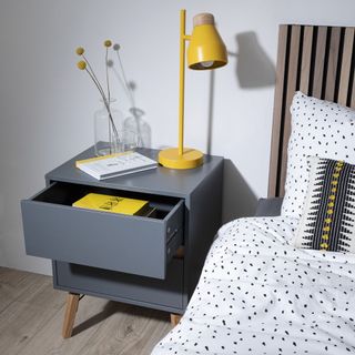 Grey bedside table with yellow lamp and drawer open