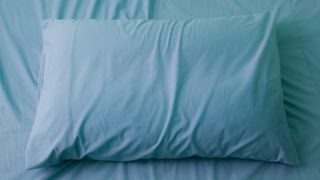 How to choose bedroom wall colors that promote better sleep: An image showing a bed pillow dressed in blue linens