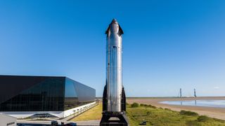 a chrome spaceship stands on in front of a sleek black building.