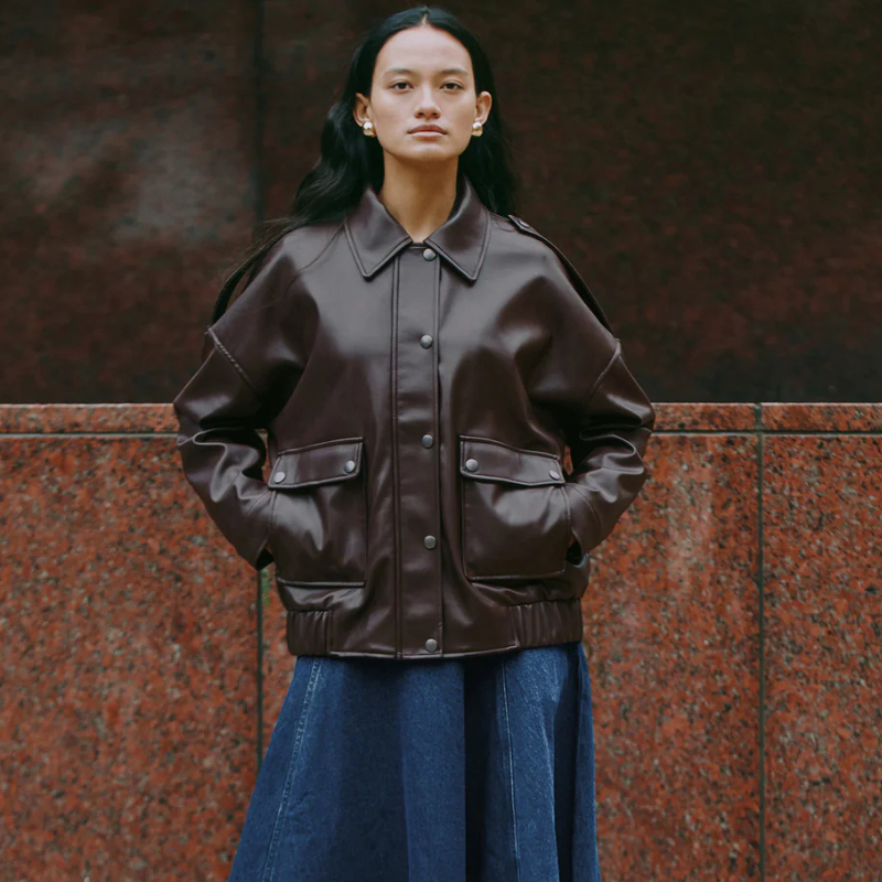 A woman wearing an oversized brown leather jacket