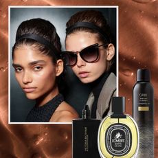 two models with glowing skin and black headbands posing on a copper background with a bottle of foundation, a glass bottle of perfume, and a black can of hair texturizer