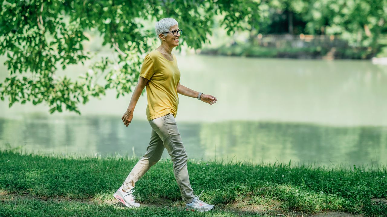 Middle-aged woman walks alongside a river