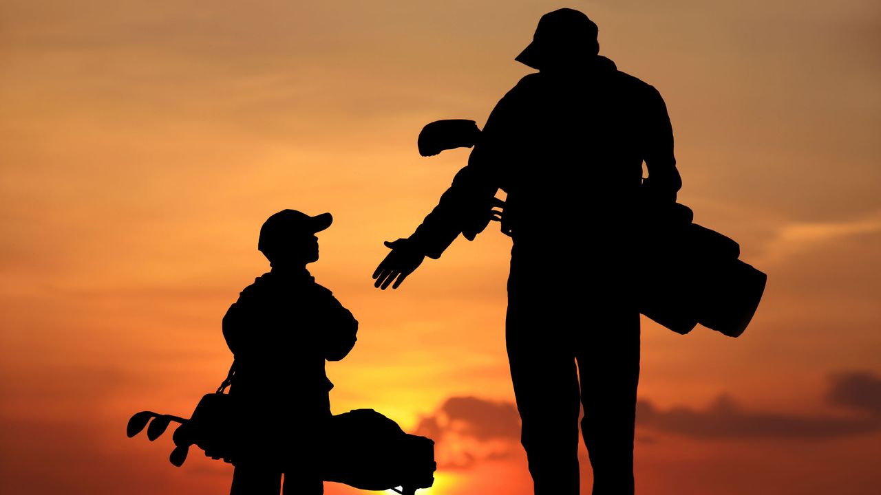 an adult golfer talking to a junior at sunset