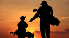 an adult golfer talking to a junior at sunset