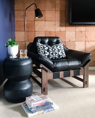 Wooden wall paneling with black leather seat, neutral carpet and contemporary black coffee table plus reading light