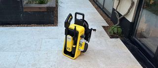 A yellow and black Karcher K5 Comfort Premium pressure washer on a clean limestone patio