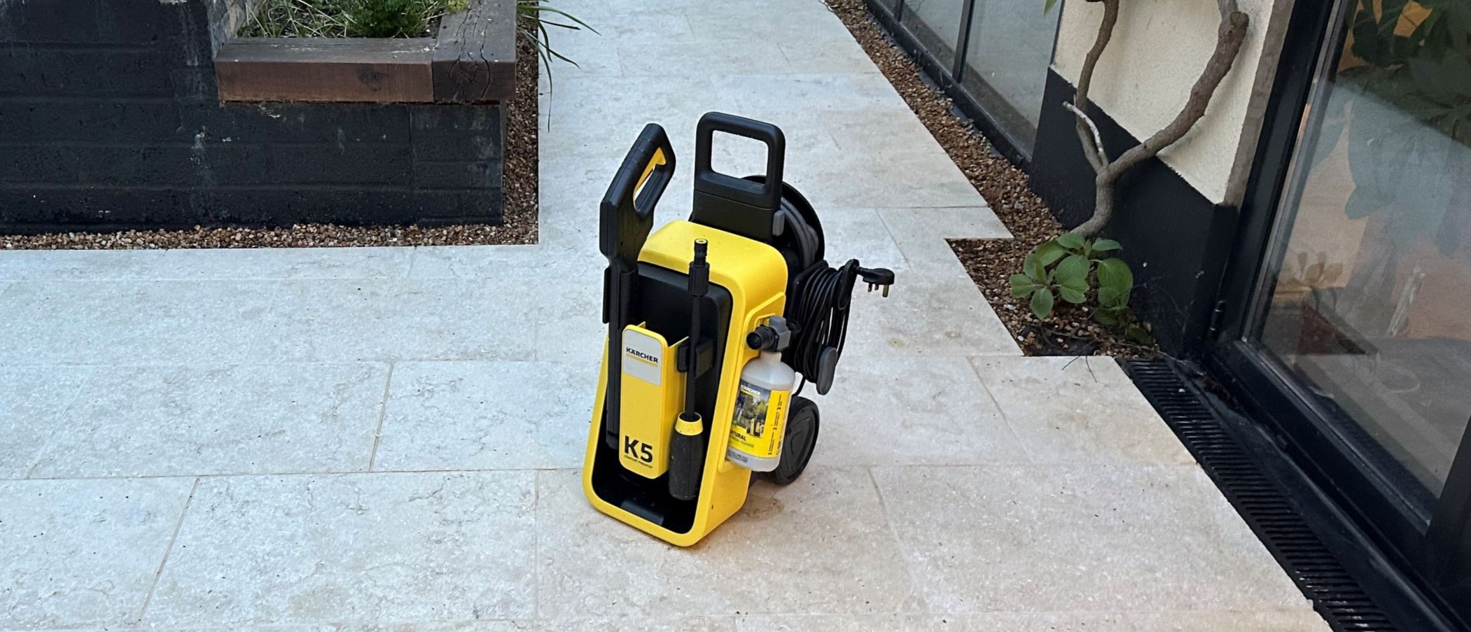 A yellow and black K&auml;rcher K5 Comfort Premium pressure washer on a clean limestone patio