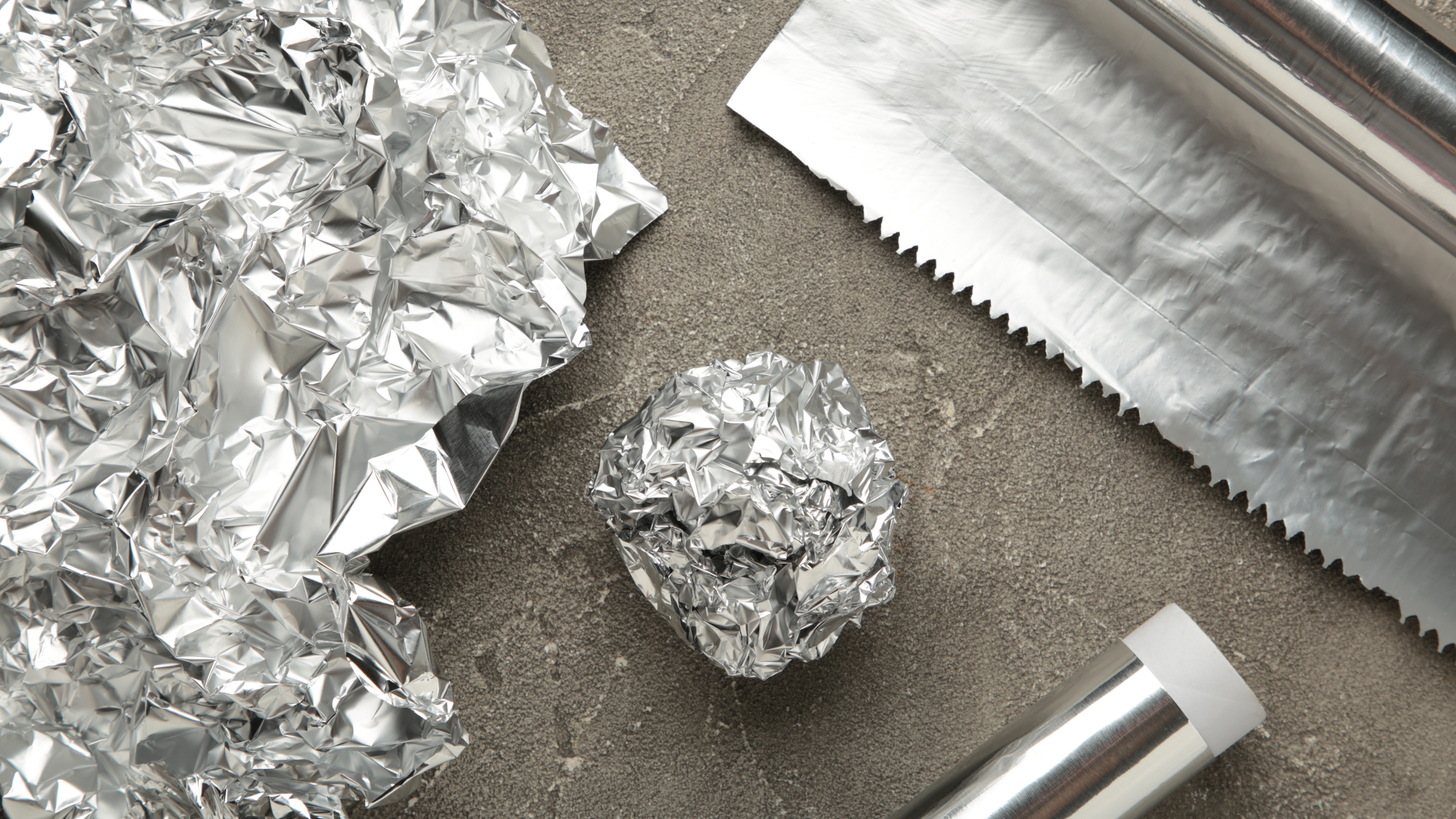 Ball of tin foil next to rolls of foil
