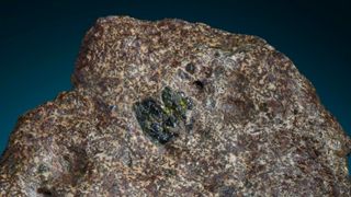 The EC 002 meteorite is "relatively coarse grained, tan and beige," with crystals that are green, yellow-green and yellow-brown.
