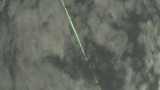 a photograph showing green laser beams against a cloudy sky