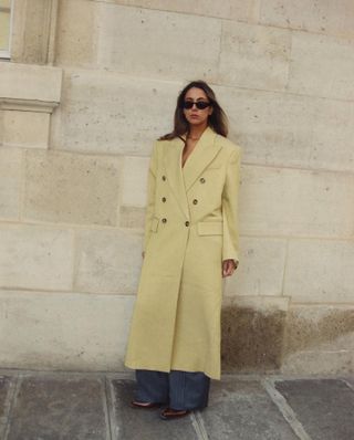 Influencer wears classic trench coat with jeans and slingback heels.