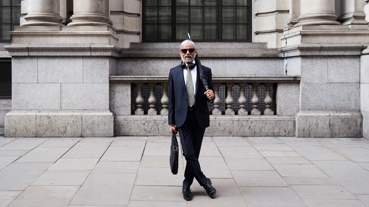 A white-haired man in a suit with a briefcase.