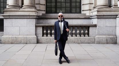 A white-haired man in a suit with a briefcase.