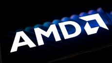 AMD logo and branding pictured on a dark reflective surface with faint blue lighting in background.