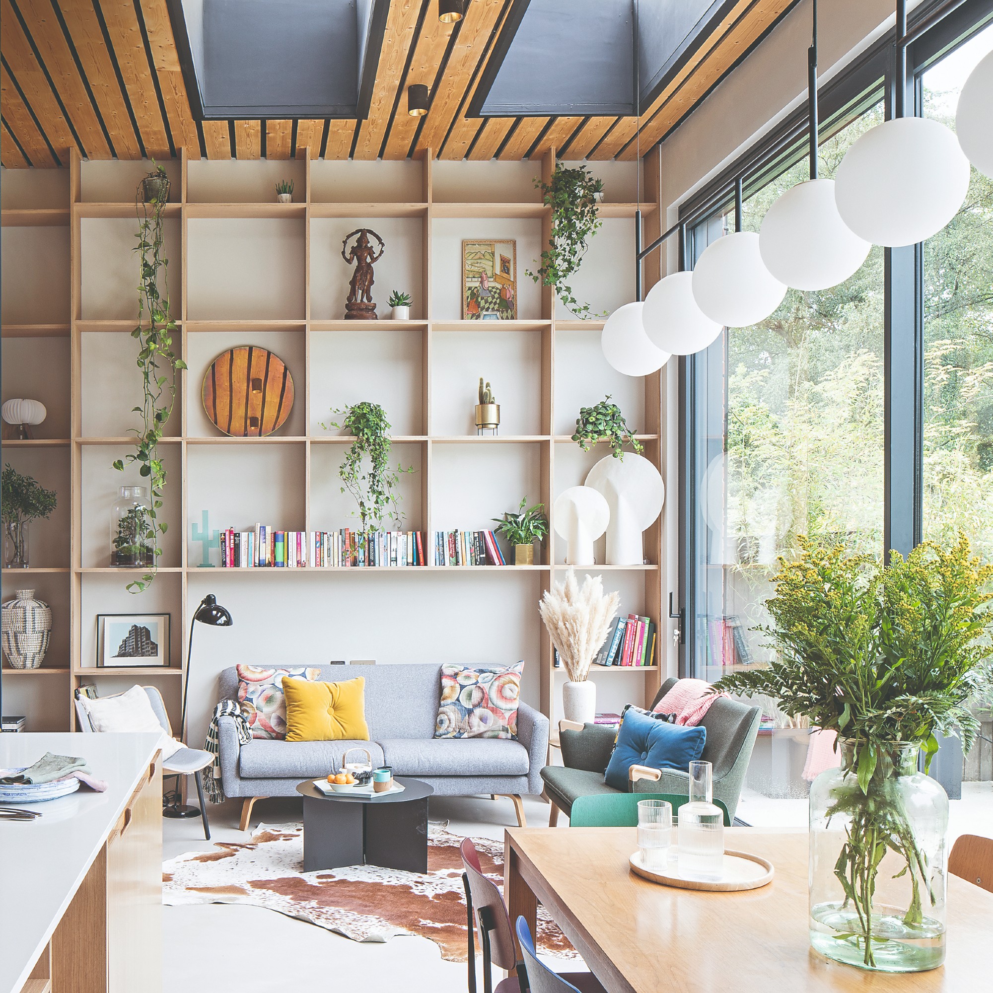 An open-plan living room with floor to ceiling windows and built-in wall storage