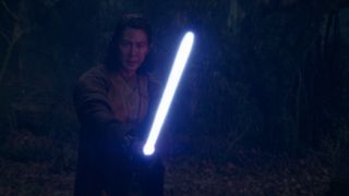 A man is holding a blue lightsaber, ready to battle.