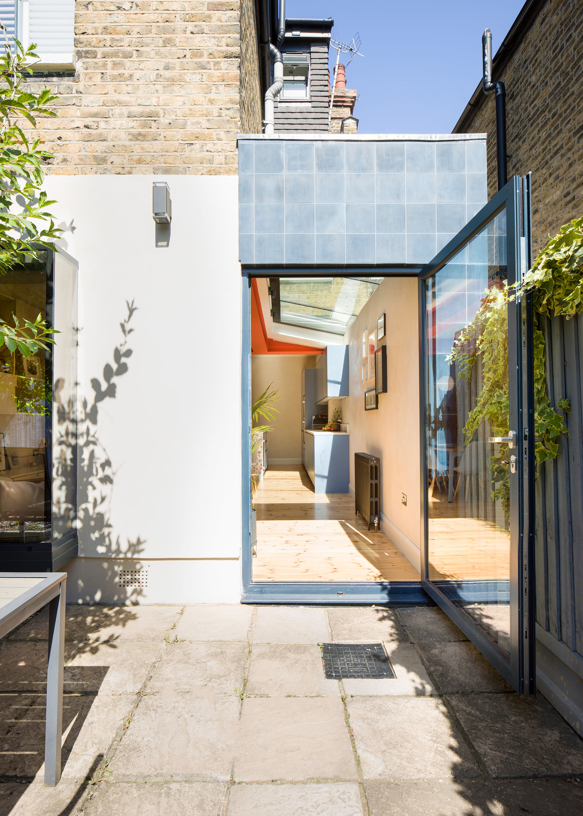 side extension with blue tile cladding and oversized pivot door