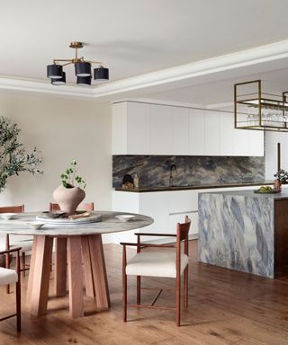 A white kitchen with turquoise countertops and backsplash and a small dining area with a wooden table