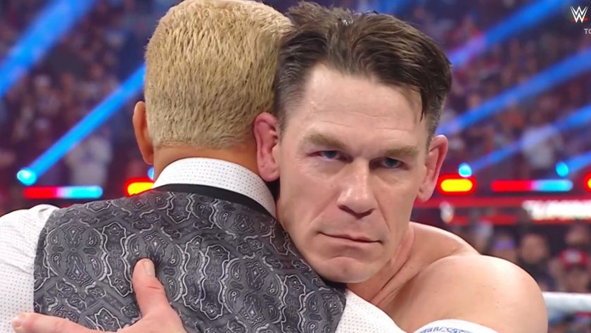 John Cena hugs Cody Rhodes with a villainous face.