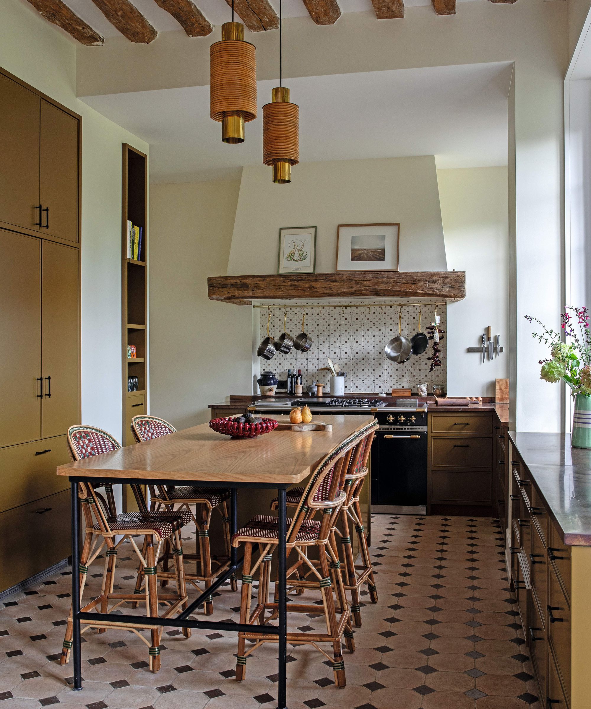 a french rustic kitchen with green ochre cabinetry, ceiling beams and stone floors
