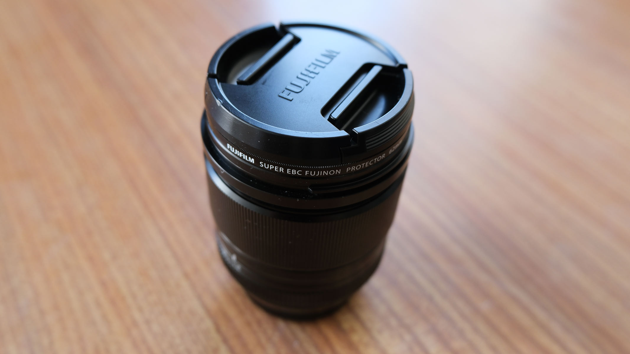 The Fujifilm XF 18mm f/1.4 lens on a table with lens cap