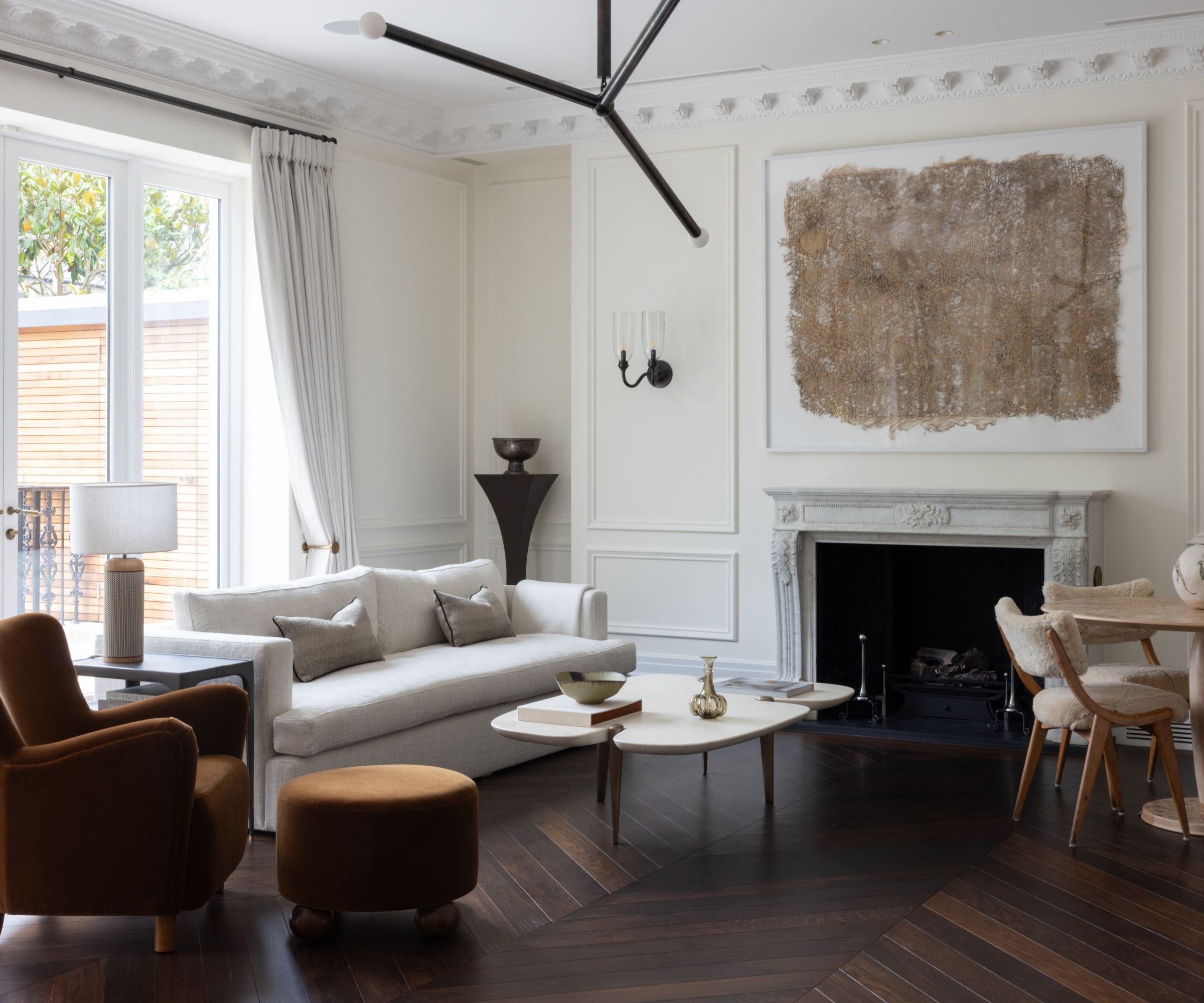 Neutral living room with wall paneling and large fireplace with print above
