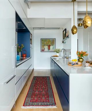white gloss kitchen with blue gloss ktichen island and a vintage runner rug