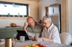 Elderly couple at table looking at laptop