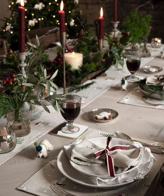 Dining table dressed with Christmas ornaments, christmas foliage and tableware