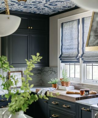 Corner of a dark blue kitchen with blue blinds over the traditional windows