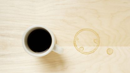 A coffee cup on wooden coffee table with coffee ring stain mark