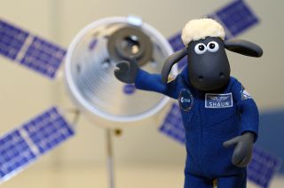 Shaun, the title character from the Aardman stop-motion TV series "Shaun the Sheep," poses with a model of the Orion spacecraft and European service module. Shaun is flying in the Artemis 1 Official Flight Kit (OFK) on behalf of ESA (European Space Agency).