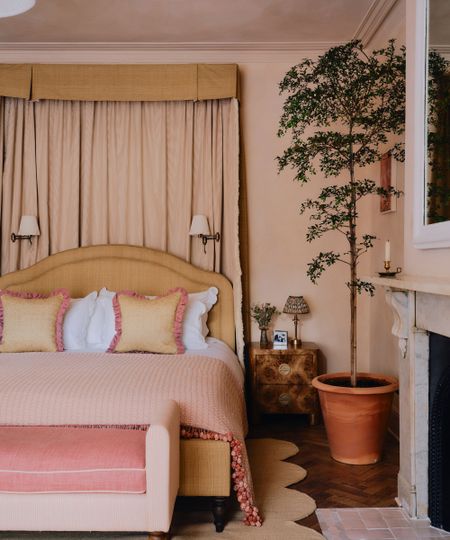 Bedroom with plaster pink walls, wooden parquet fllor, large marble fireplace and pink tiles on the floor, a yellow canopy bed, a mustard yellow bed with pink and white bedding and a pink daybed