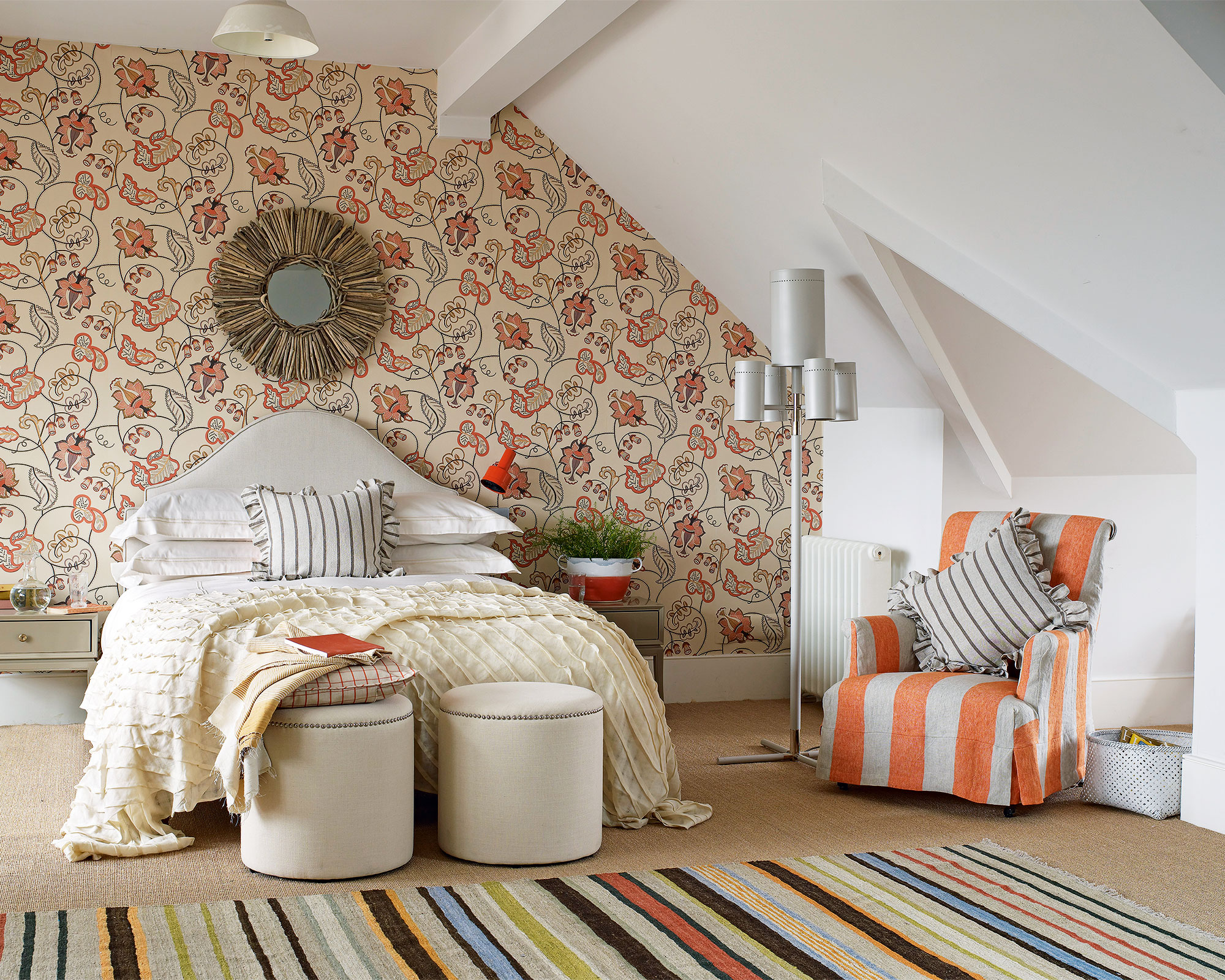 A white loft bedroom with statement wallpaper and striped rug illustrating small bedroom ideas.