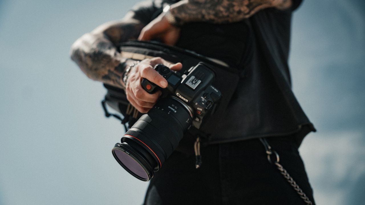 A photographer grabs a Canon camera out of the PolarPro RoadRunner Shoulder Bag