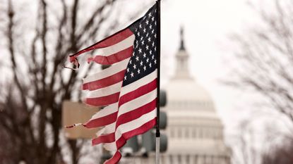 Photograph of a broken American flag with the US capitol in the background