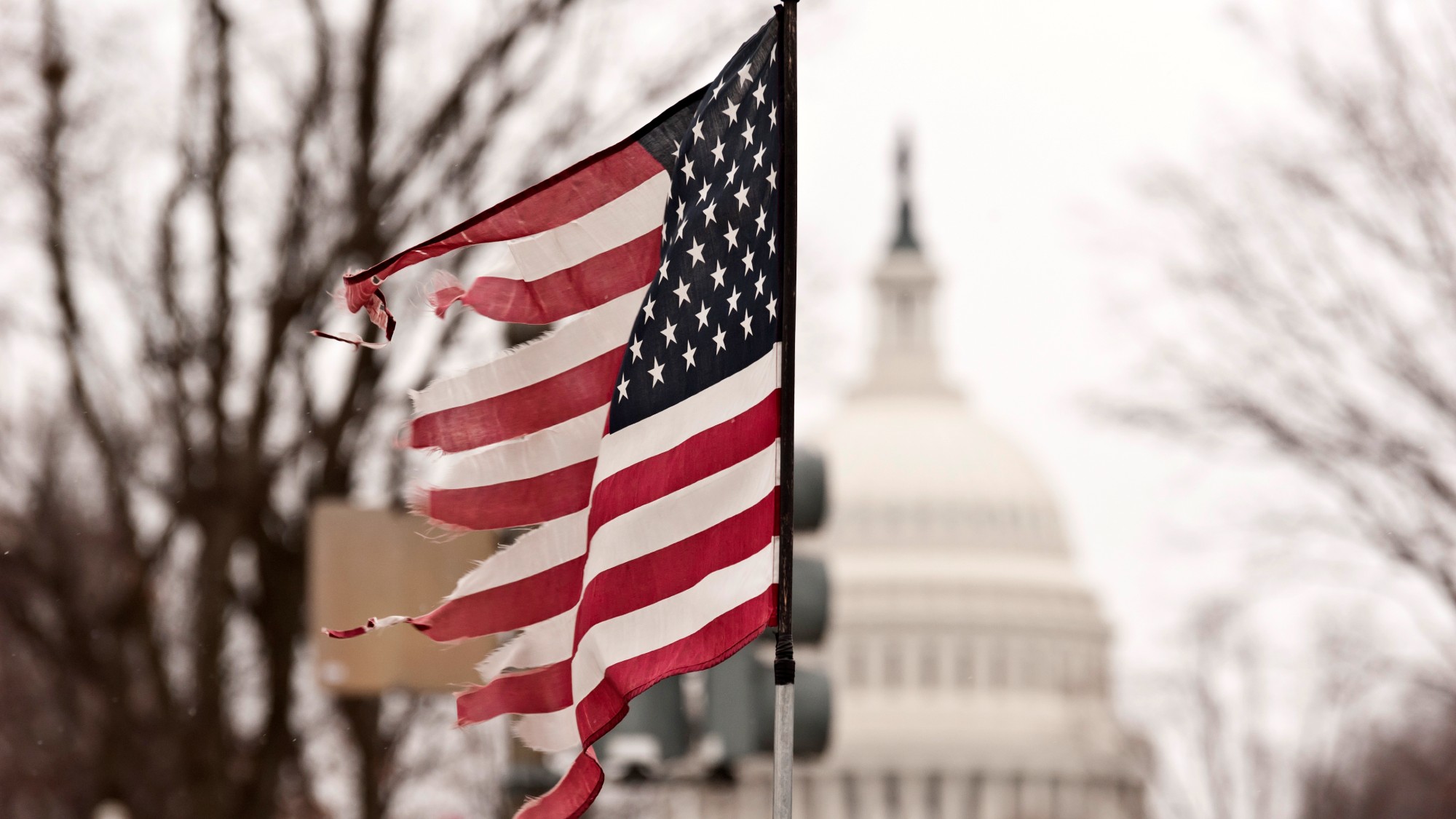 Photograph of a broken American flag with the US capitol in the background