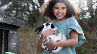 Child holding black and white rabbit 