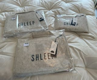 Bags of Shleep bedding on a Naturepedic Mattress Topper.