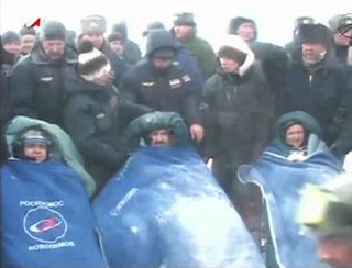 The crew of Russia's Soyuz TMA-01M space capsule is bundled up in blankets while readjusting to Earth's gravity after 159 days in space. The Soyuz landed March 16, 2011 carrying NASA astronaut Scott Kelly (right) and Russian cosmonauts Alexander Kaleri (center) and Oleg Skripochka back to Earth from the International Space Station.