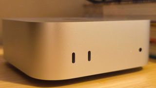 A silver Apple Mac mini (M4) on a wooden desk