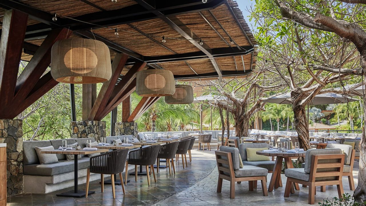 Image of an outdoor dining area with a bamboo awning and rattan lighting fixtures.