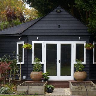 summer house with potted plants and dark exteriors