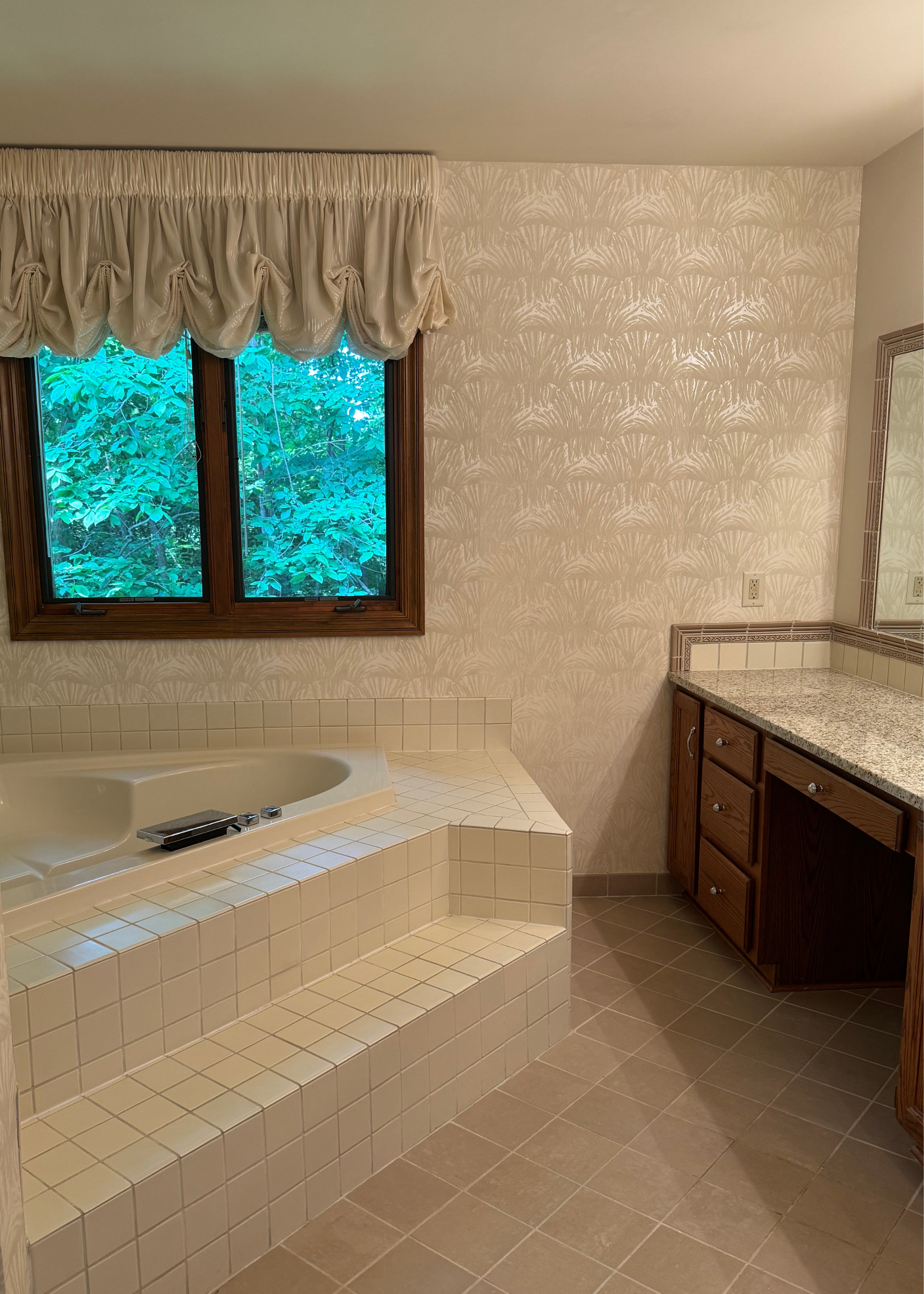 a step up tiled bath in a curtained, wallpapered bathroom