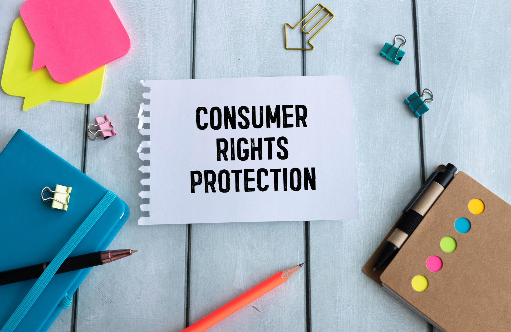 a white banner reading consumer rights protection next to a blue notebook and post-it notes