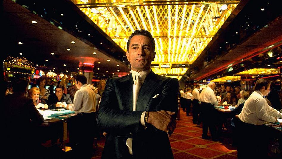 A still from the movie Casino in which Robert DeNiro's character Sam "Ace" Rothstein is stood in a casino in a suit, looking pensive.